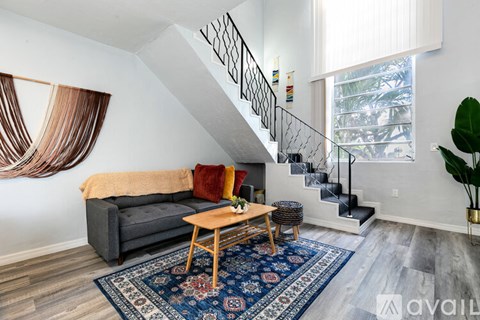 A living room with a grey couch, a wooden coffee table, and a rug.