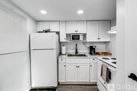 A kitchen with white appliances and cabinets.