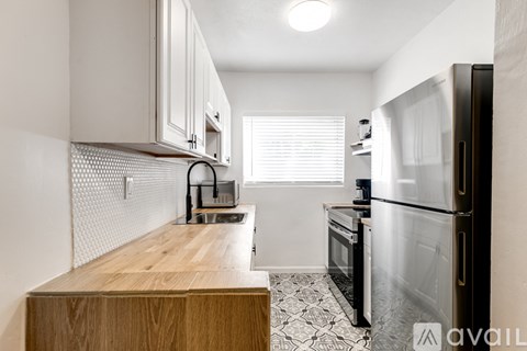 A kitchen with a wooden countertop and a black refrigerator.