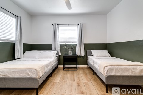 Two beds in a room with wooden floors and white walls.