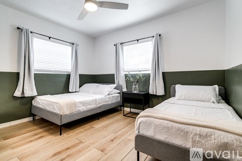 A bedroom with two beds and a ceiling fan.