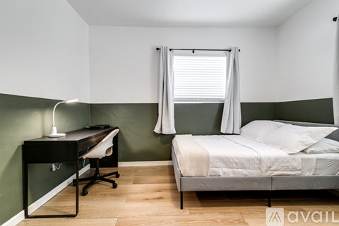 A bedroom with a bed, desk, and chair.