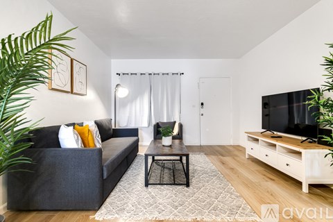 A living room with a grey couch, a black coffee table, and a television on a wooden stand.