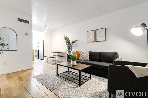 A living room with a black couch, a coffee table, and a rug.