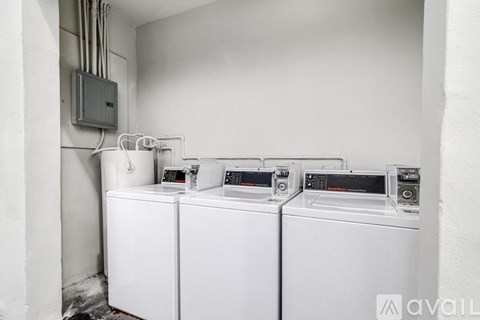 A row of washing machines are lined up in a laundry room.