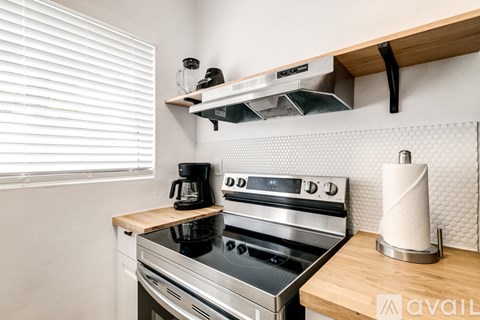 A modern kitchen with a stove top oven and a wooden counter.