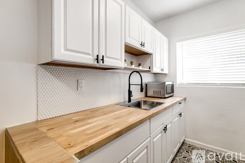 A kitchen with white cabinets and a wooden counter top.
