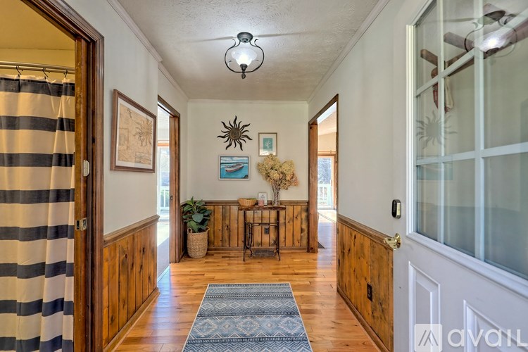 A hallway with a striped shower curtain on the left and a rug on the floor.