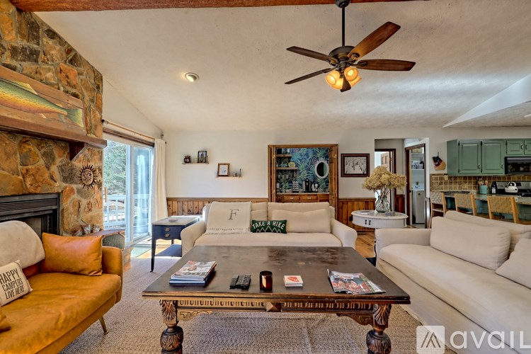 A living room with a stone fireplace and a wooden coffee table.