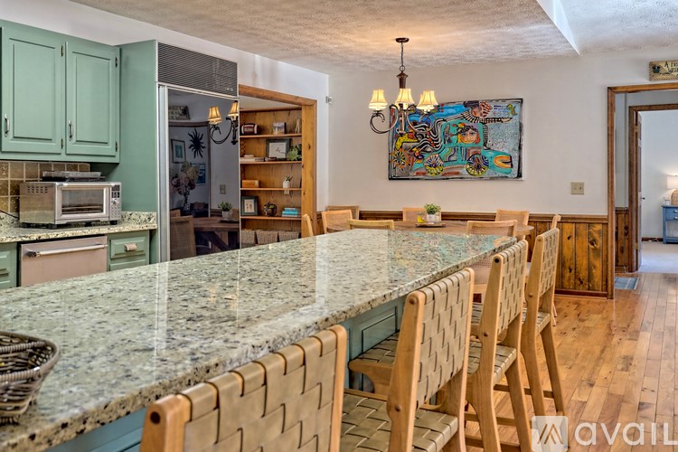 A kitchen with a granite countertop and wooden chairs.