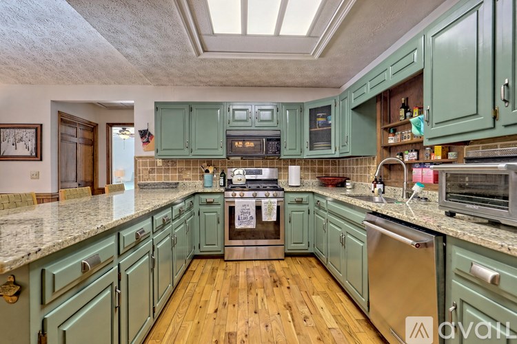 A kitchen with green cabinets and a wooden floor.