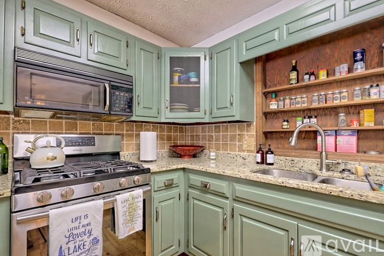 A kitchen with green cabinets and a tile backsplash.