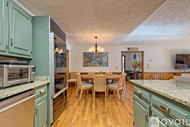 A kitchen with wooden floors and a dining table with chairs.
