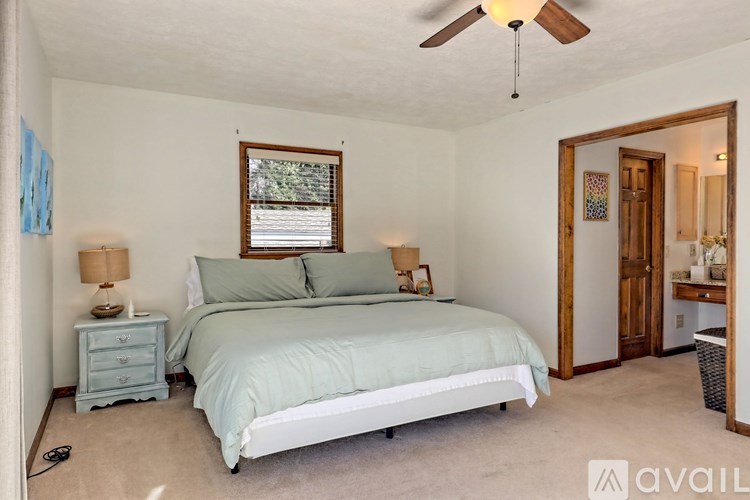 A bedroom with a bed, nightstand, and window.