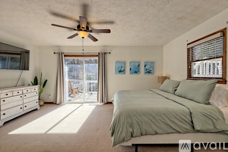 A bedroom with a bed, dresser, and a ceiling fan.