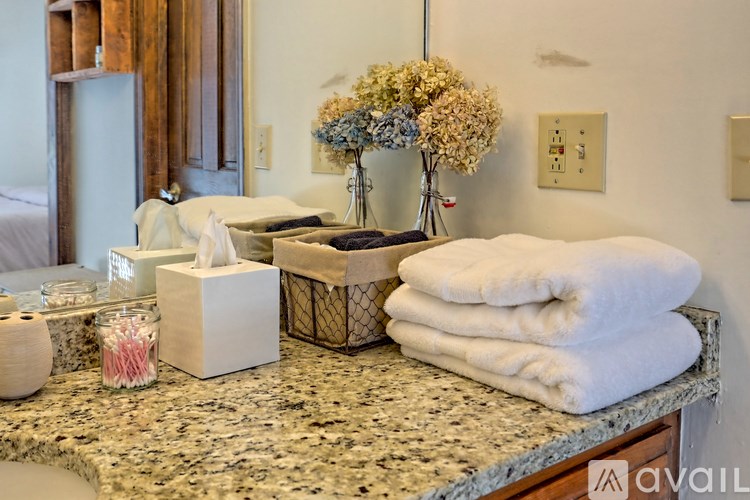 A bathroom counter with towels, a vase with flowers, and a tissue box.