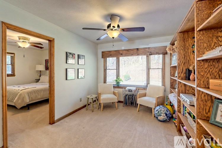 A bedroom with a bed, chair, and a ceiling fan.