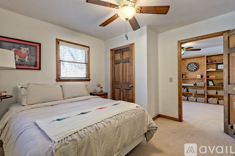 A bedroom with a bed, a ceiling fan, and a painting of a dog on the wall.