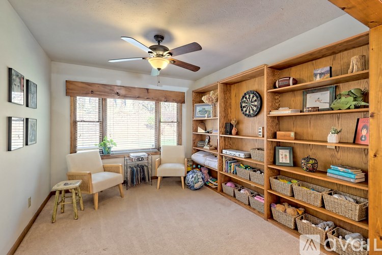 A room with a ceiling fan and a large shelf with various items on it.