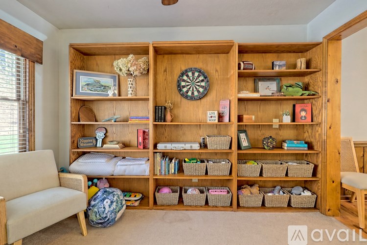 A room with a couch, a dartboard, and a wooden shelf with various items on it.