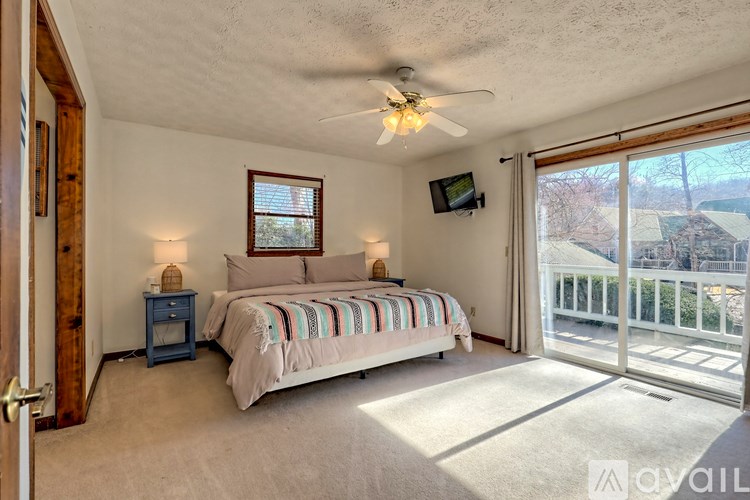 A bedroom with a bed, a ceiling fan, and a sliding glass door leading to a balcony.