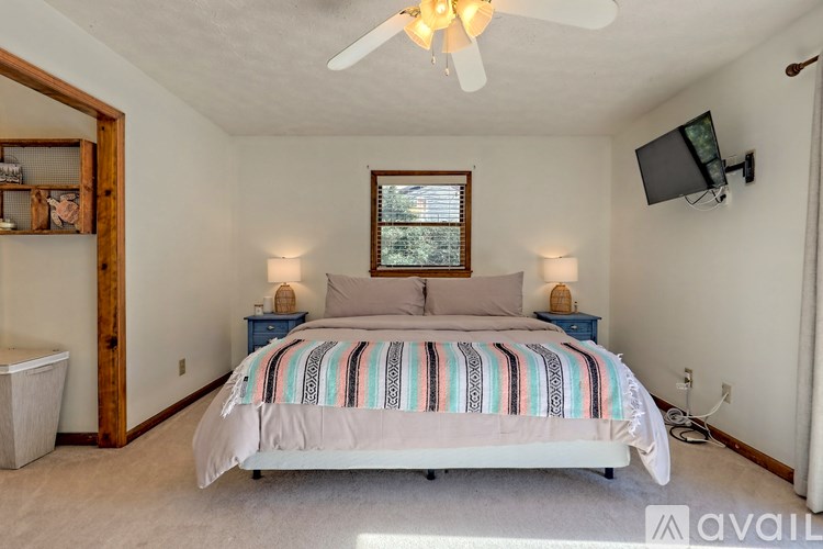 A bedroom with a bed, a ceiling fan, and a window.