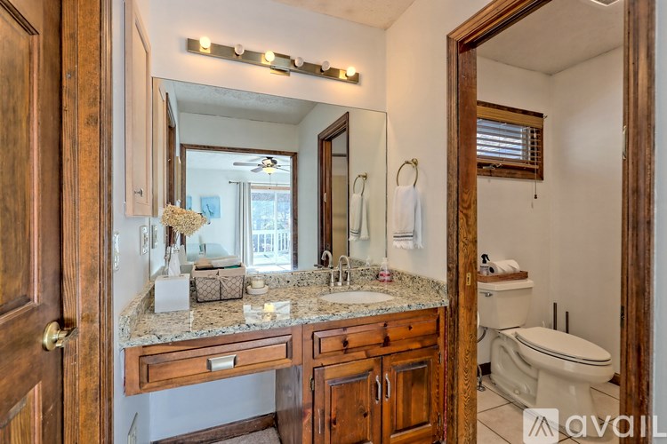 A bathroom with a granite countertop and a mirror above it.