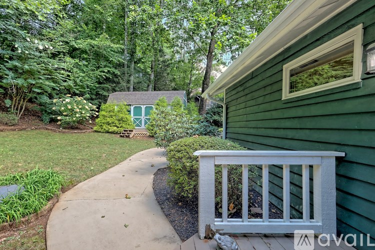 A green house with a white railing and a small garden area.