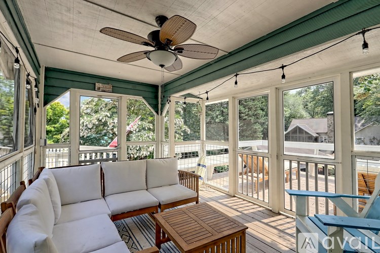 A white couch is on a wooden deck with a ceiling fan.