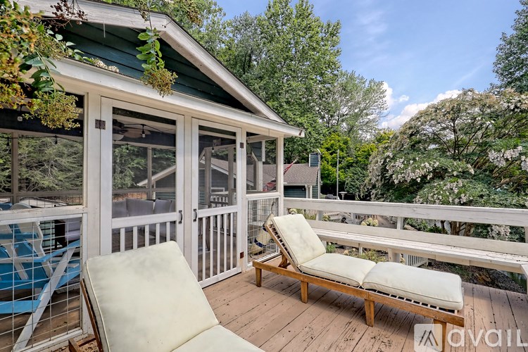 A sunny day at a wooden deck with a white chair and a small house.