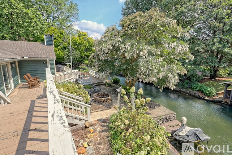 A deck overlooks a pond and a house.