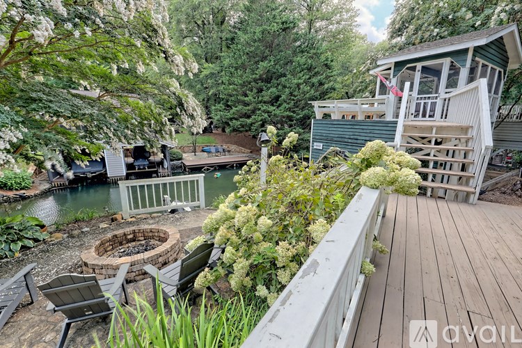 A wooden deck overlooks a pond with a fire pit in the middle.