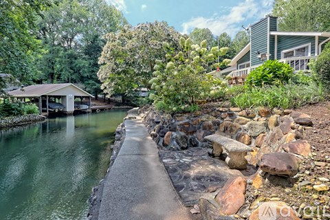 A house is situated by a body of water with a concrete walkway leading to it.