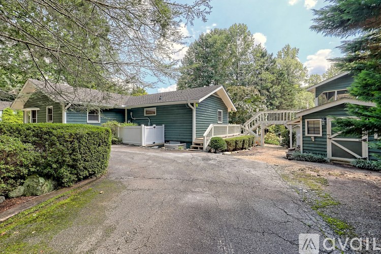A driveway leads to a house with a garage door and a tree in the background.