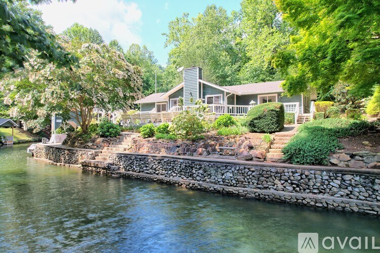 A house is situated on the waterfront with a stone wall in front.