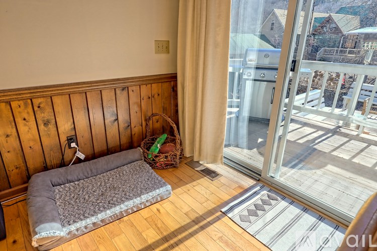 A room with a wooden wall and a window with a view of a snowy landscape.