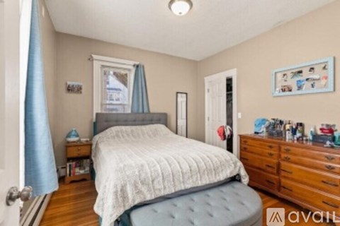 A bedroom with a bed, dresser, and a window with a blue curtain.