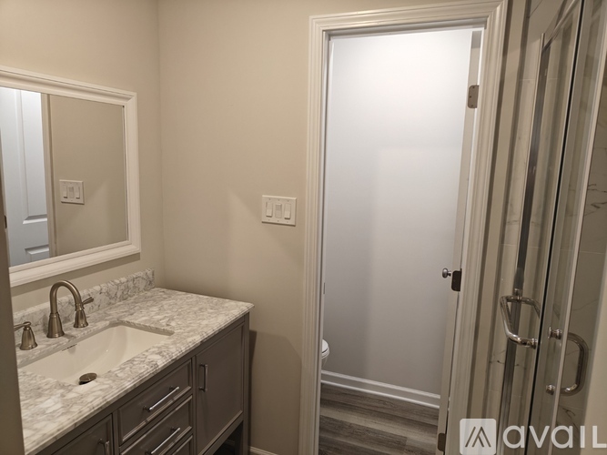A bathroom with a sink, mirror, and shower.