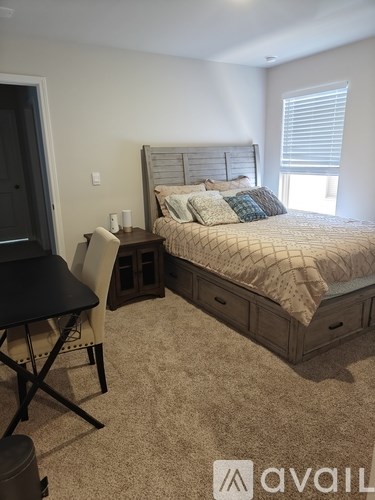 A bedroom with a bed, chair, and table.