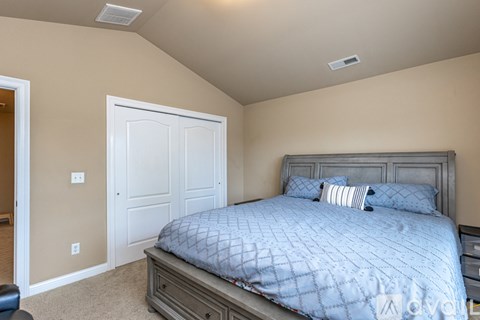 A bedroom with a bed, nightstand, and chair.