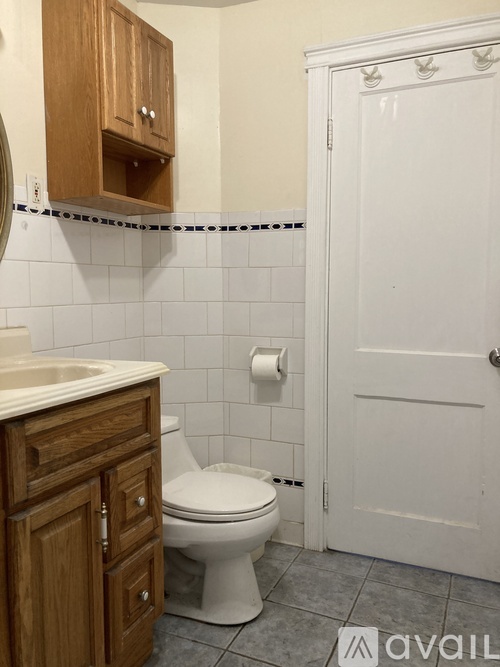 A white toilet in a bathroom with a wooden cabinet above it.