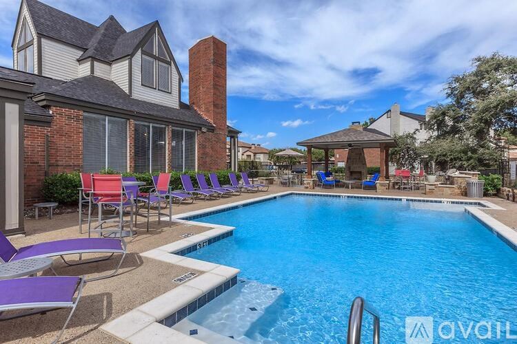 A pool with chairs around it and a house in the background.