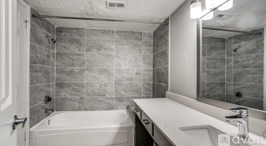 A bathroom with a tub, sink, and mirror.