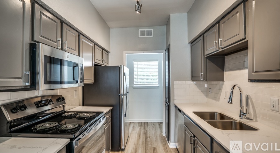 A kitchen with a black refrigerator and stove top oven.