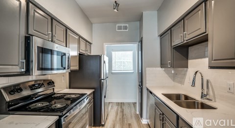 A kitchen with a black refrigerator and stove top oven.