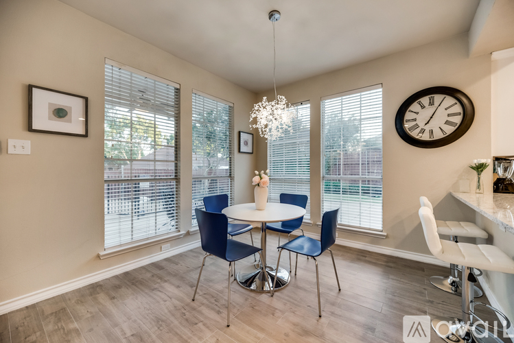 A dining room with a table set for four and a chandelier hanging from the ceiling.