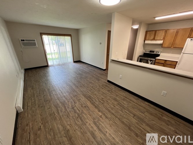 A spacious living area with wood flooring and a kitchenette.