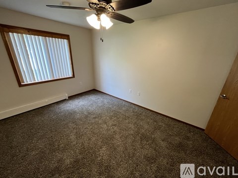A room with a ceiling fan and a window with blinds.