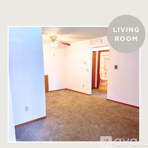 A living room with a carpeted floor and a ceiling fan.
