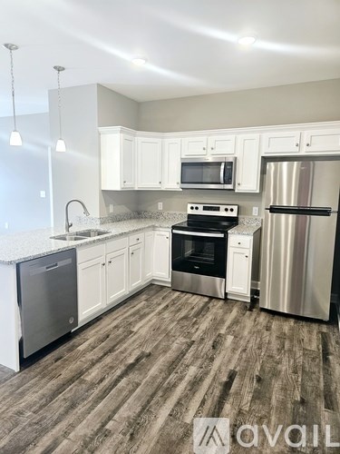 A kitchen with white cabinets and a wooden floor.